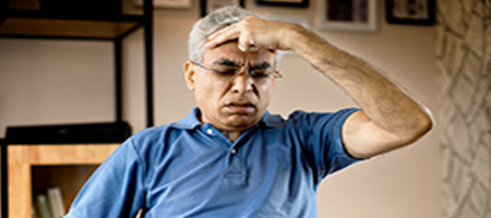 Senior man suffering from a headache with hand to head and anguished face.