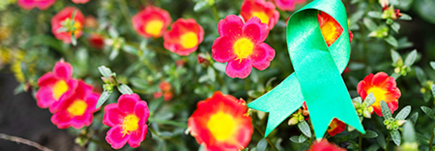 Green ribbon representing mental health awareness on flower blooms.
